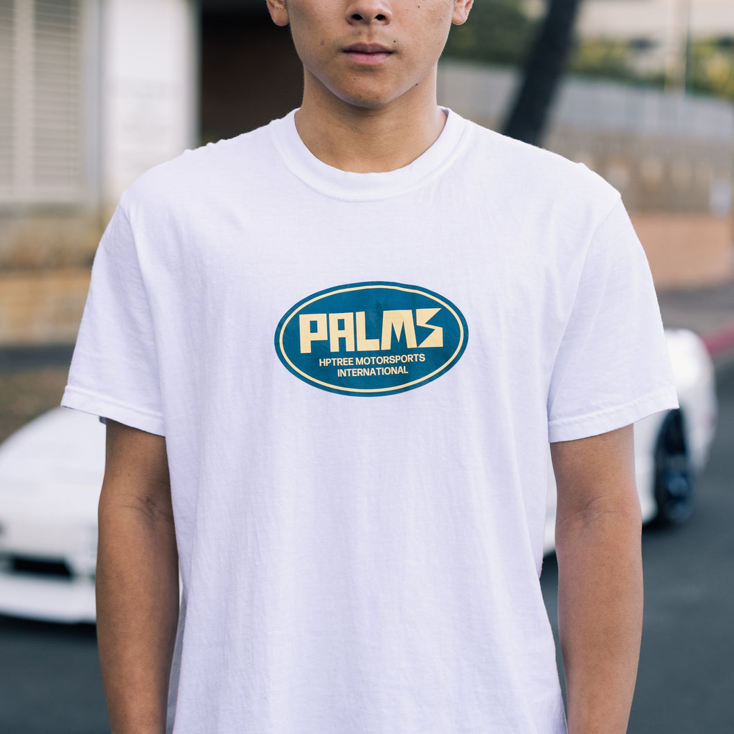 Person wearing a white t-shirt with 'PALMS' logo outdoors.
